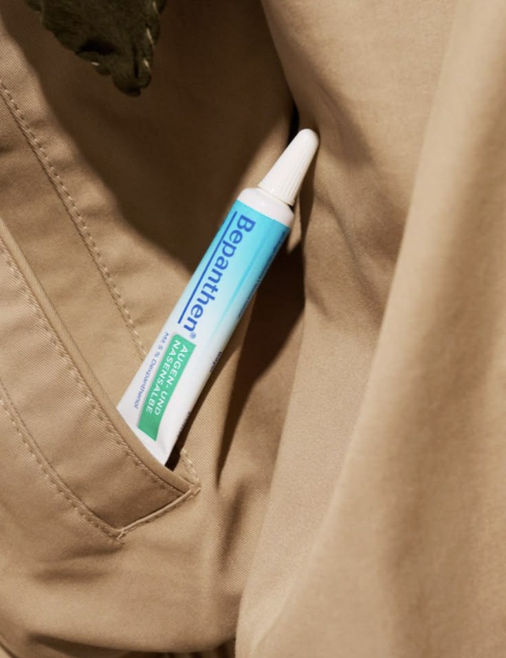 Bepanthen Augen- und Nasensalbe tube tucked into a tan trench-coat pocket