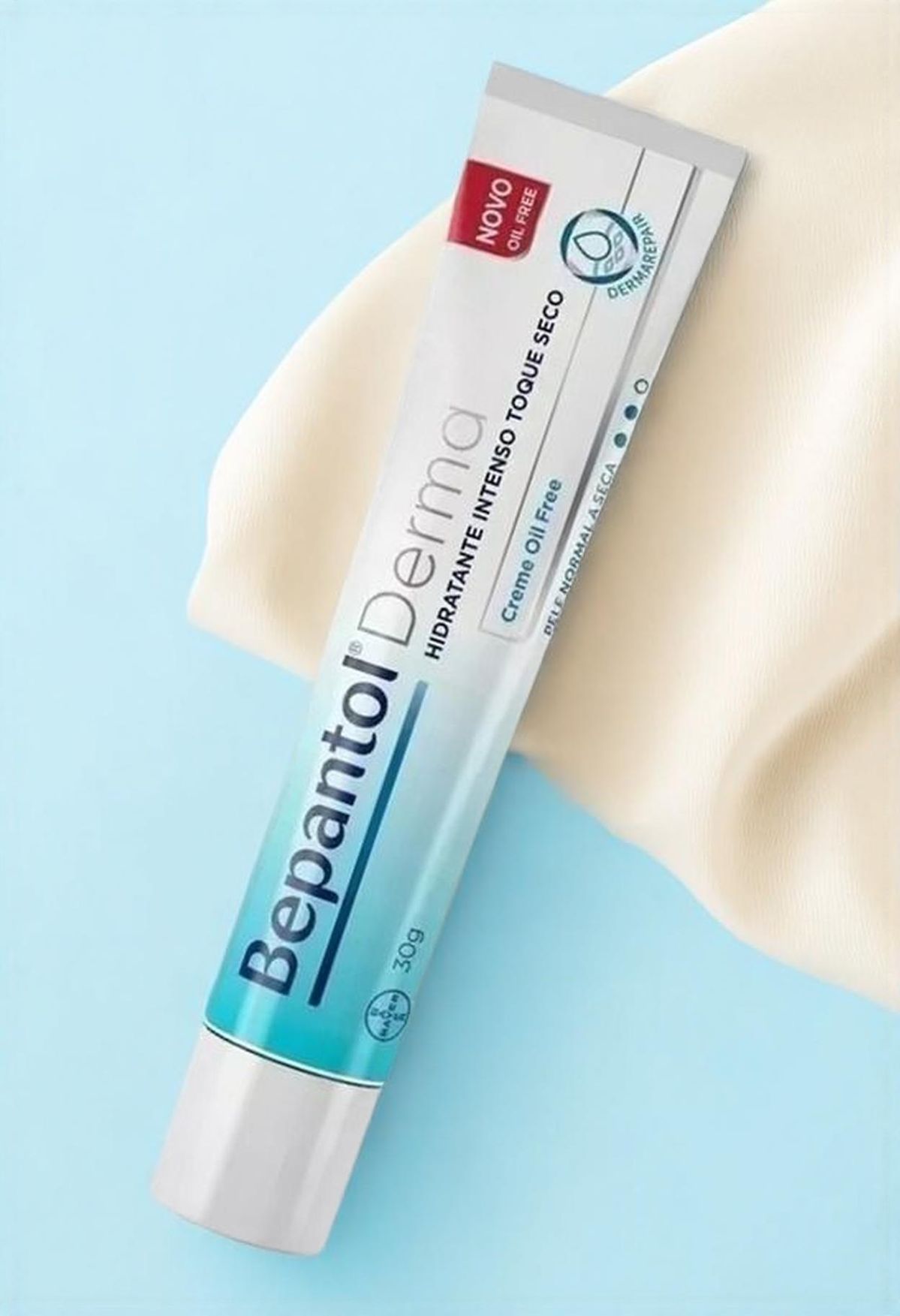 Bepantol Derma tube on cobalt blue with cream silk drape — clinical studio still