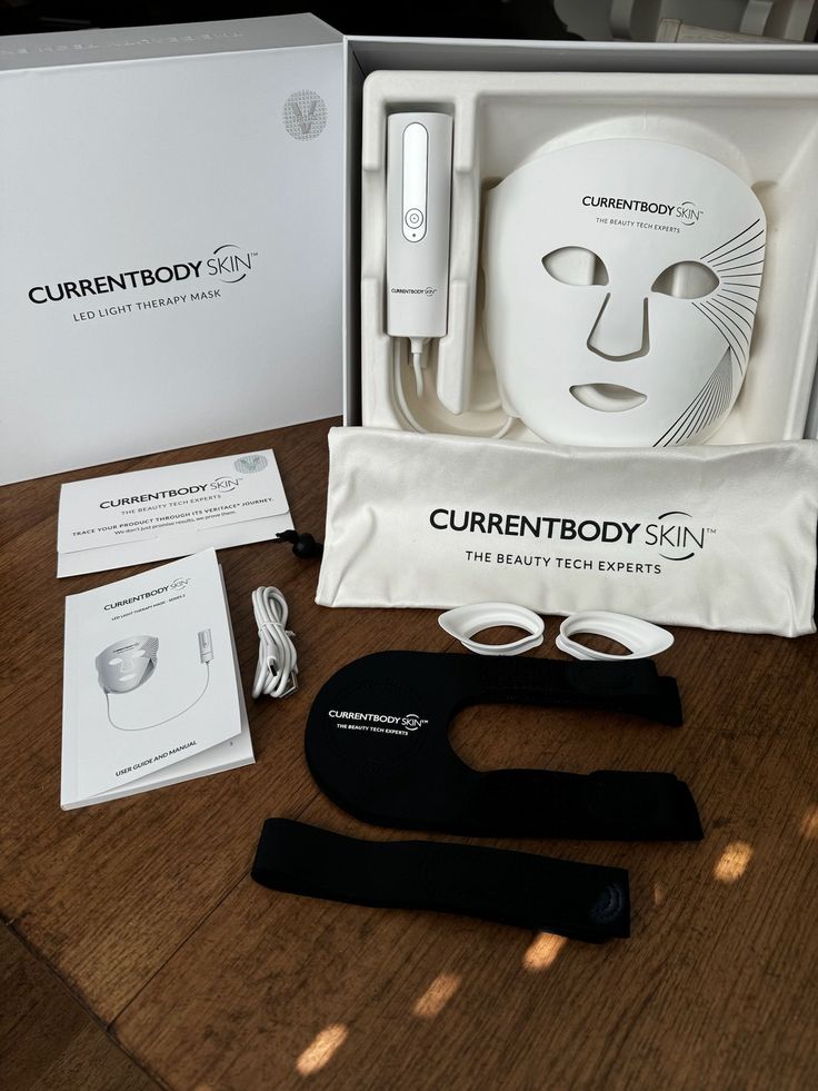 CurrentBody Skin LED Mask unboxing flatlay on wood — the full kit and pouch