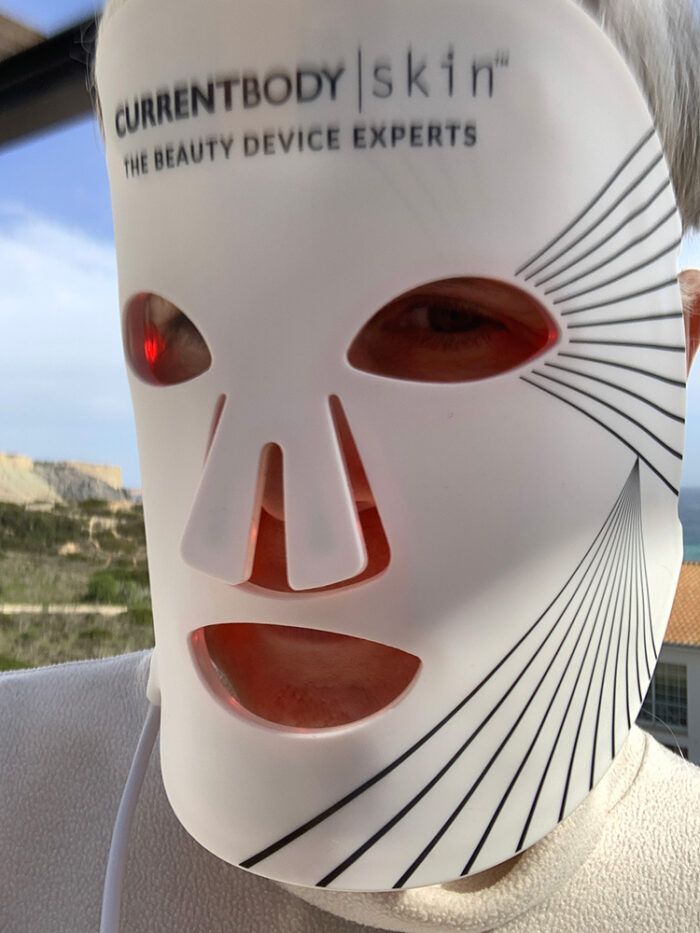 CurrentBody Skin LED Mask worn with a Mediterranean view — the British brand on holiday