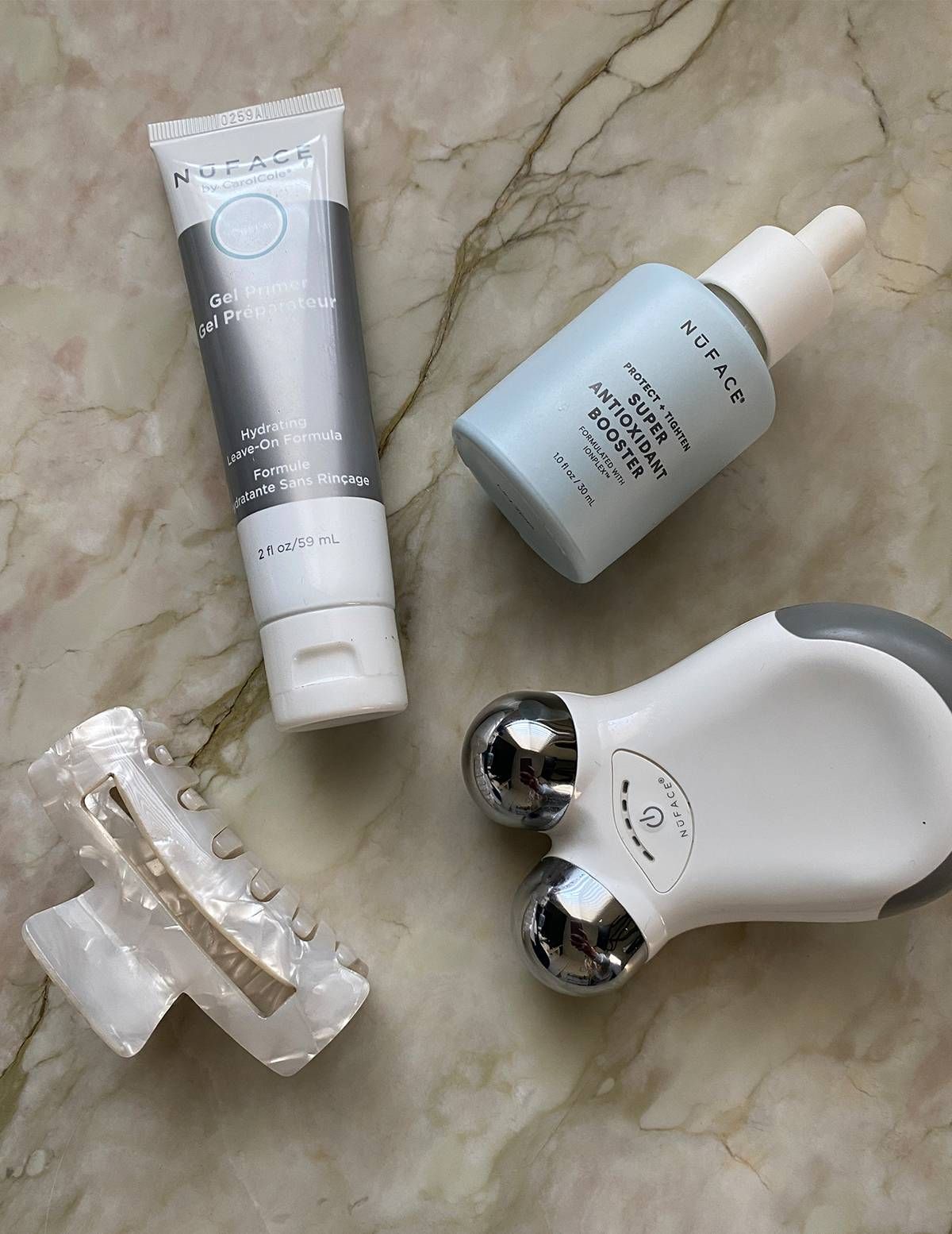 NuFACE Mini, Gel Primer and Antioxidant Booster flatlay on marble — the device system