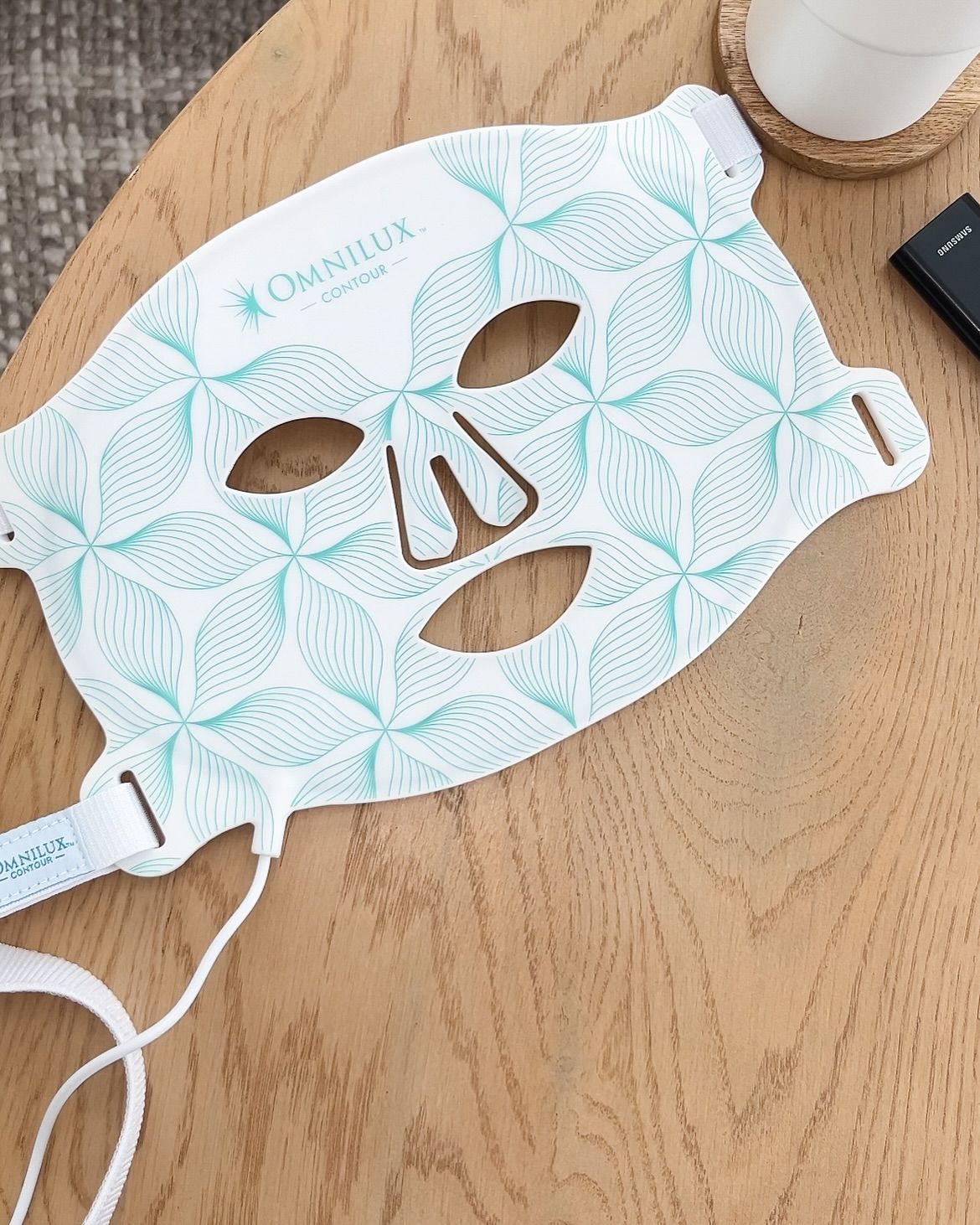 Omnilux Contour Face mask flat on wood — the clinical device at rest