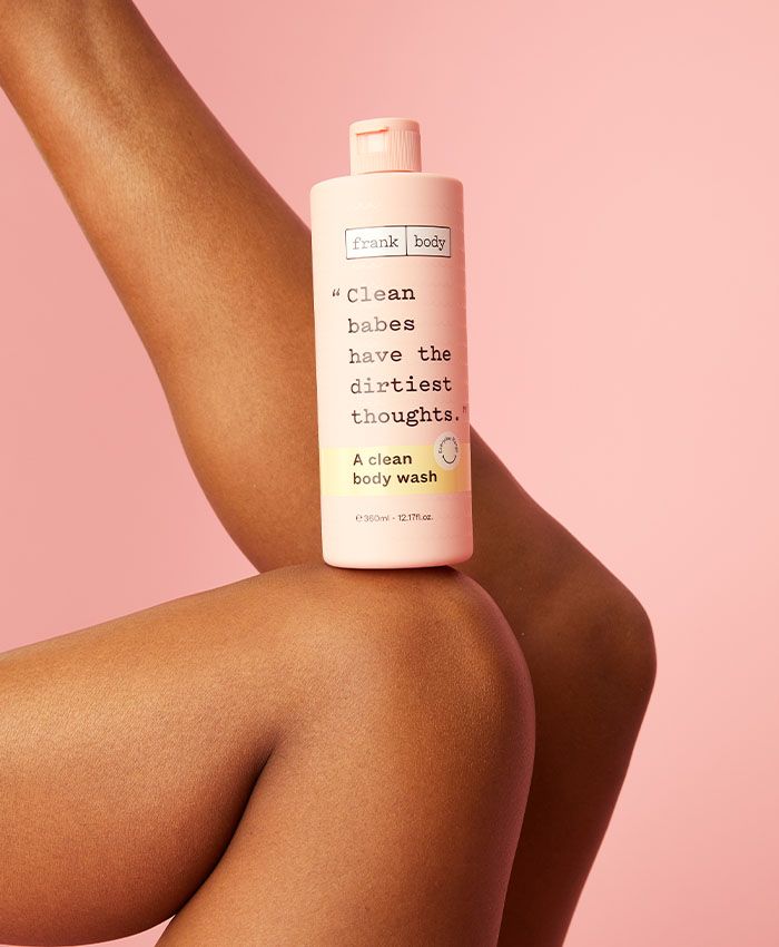 Frank Body Clean Body Wash perched on a model's leg — pink studio