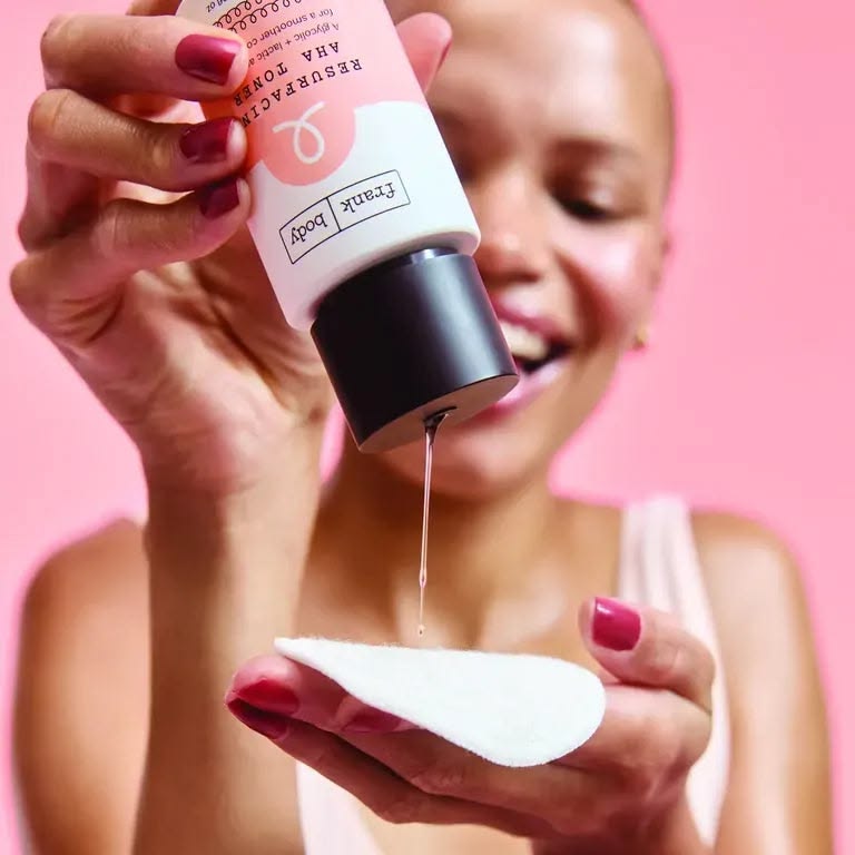 Frank Body Glycolic Body Scrub held in hand with product residue — teal studio
