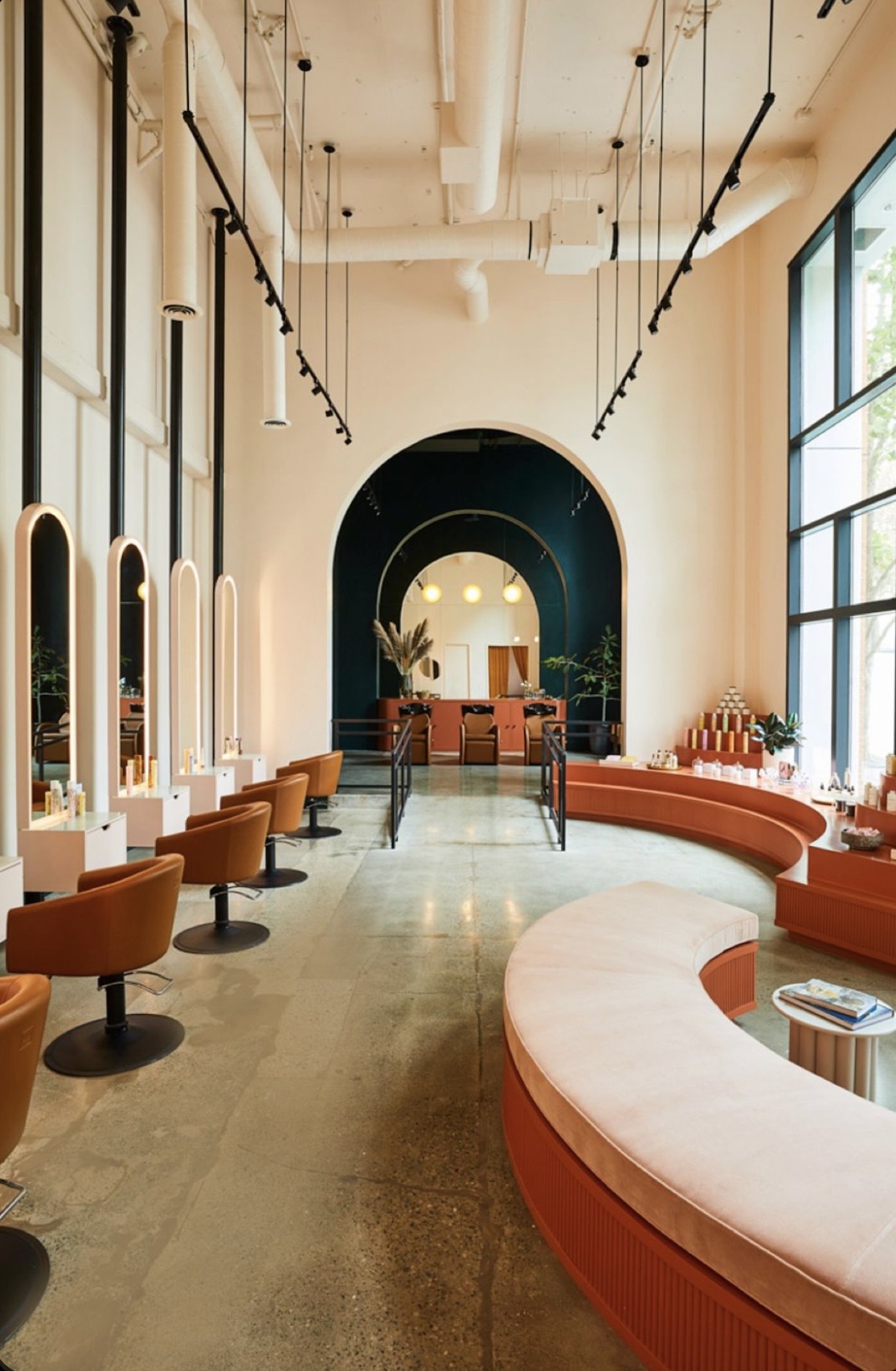 Bright contemporary hair salon with arched windows and tangerine seating