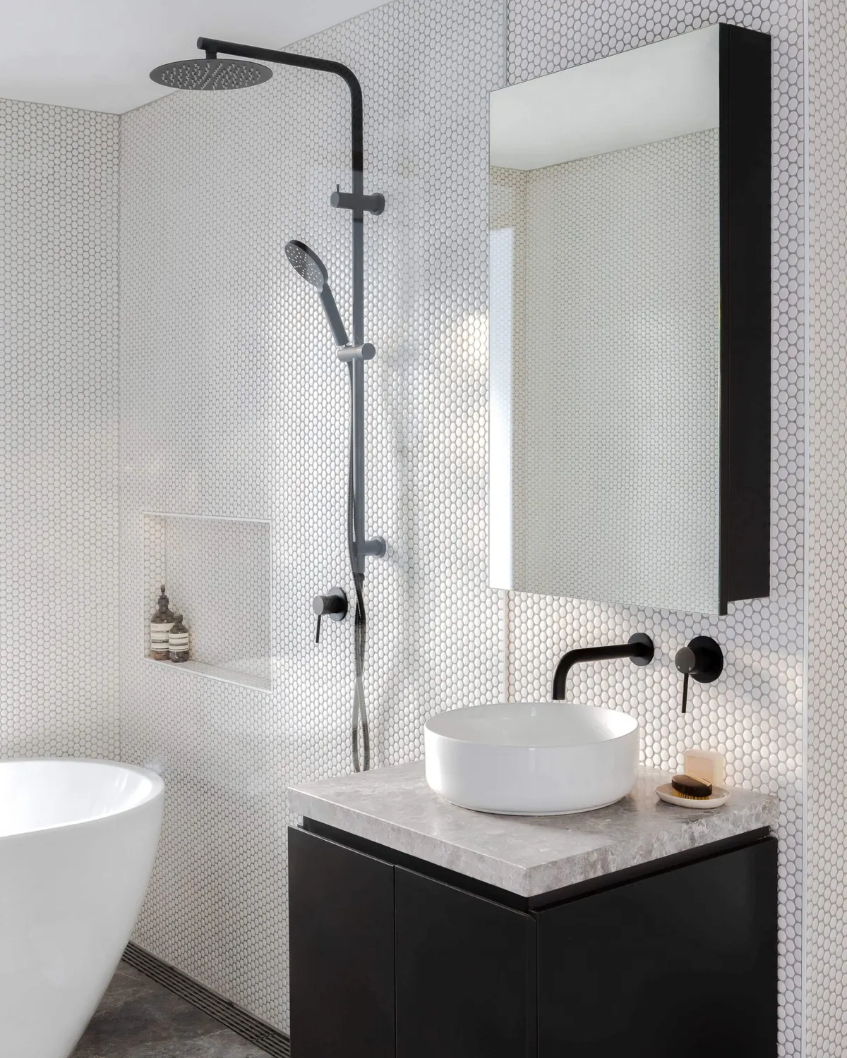 Bathroom with a freestanding bath, rain shower and penny-round tiles