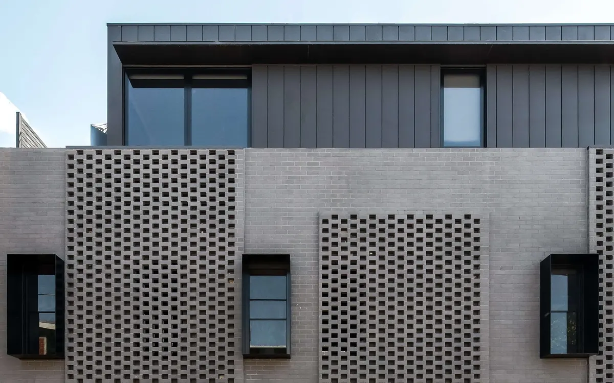 Façade detail: perforated brick panels below the metal-clad top floor