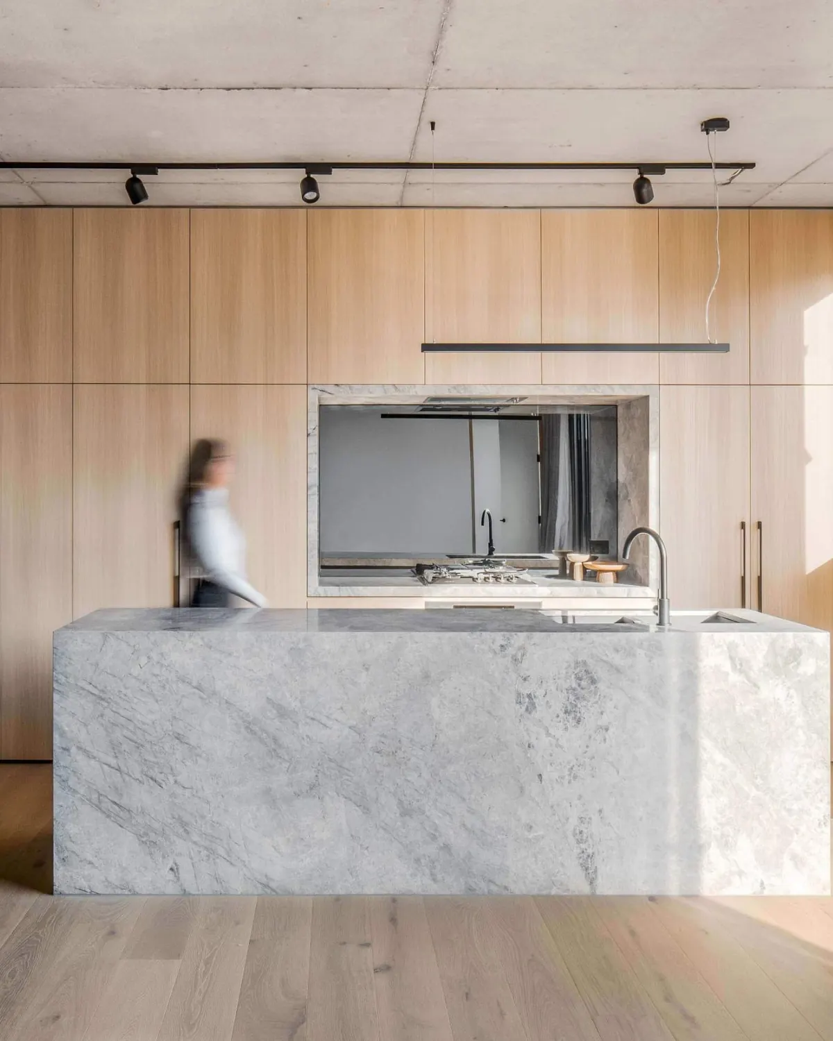 Open kitchen at GLOW House: a solid marble island before full-height oak joinery