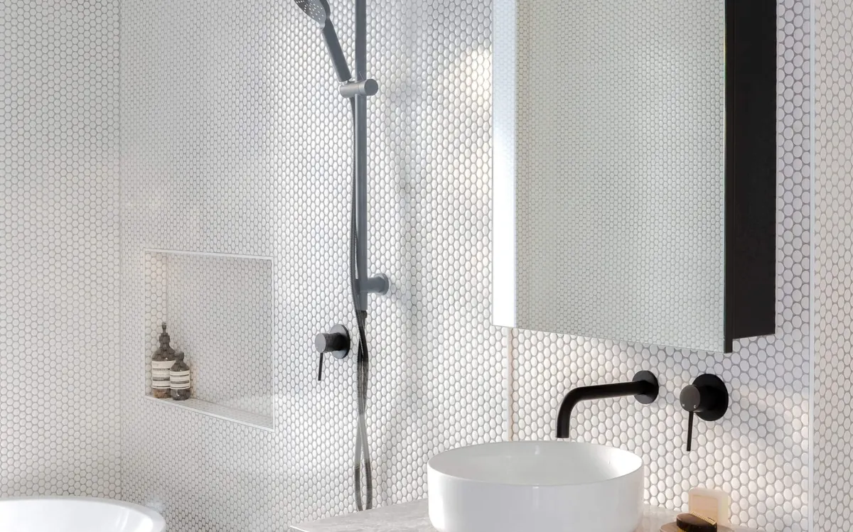 Bathroom with a freestanding bath, rain shower and penny-round tiles