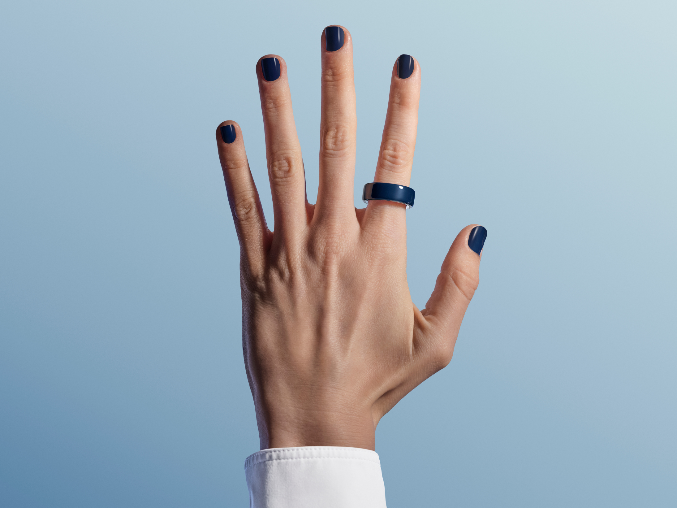 Oura Ring on hand against blue background