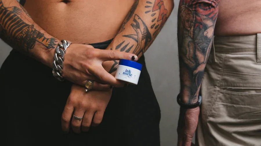 Tattooed customers holding the Ink Nurse 100ml Remedy Cream jar