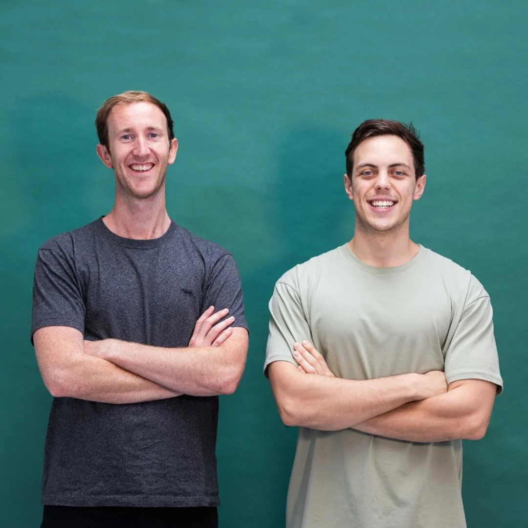 The two founders of Two Dudes, the New Zealand men's grooming brand, on a teal studio backdrop.